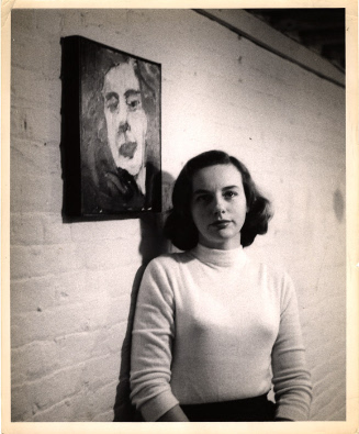 Grace Hartigan standing next to her self portrait, 1953. Image courtesy Grace Hartigan Papers m…
